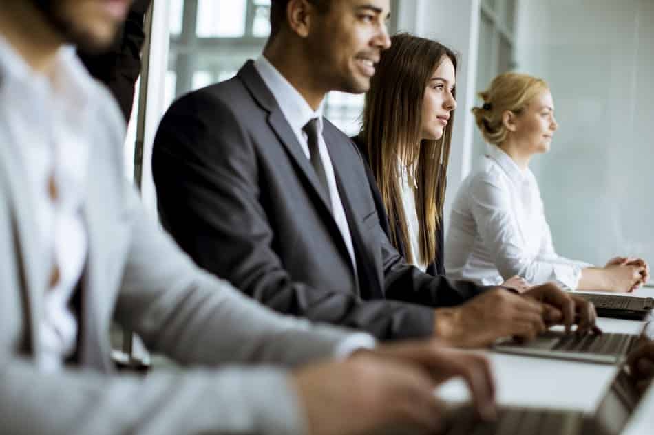 Group of professional insurance brokers working on laptops in a modern office environment